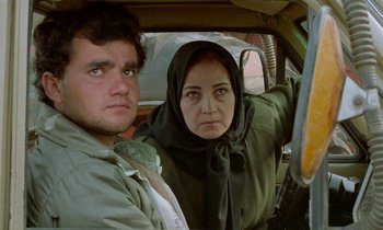 Movie still from “Through the Olive Trees” (1994), directed by Abbas Kiarostami – A man and a woman sitting in the back of a car; Close Up shot, Low angle