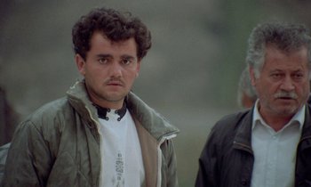 Movie still from “Through the Olive Trees” (1994), directed by Abbas Kiarostami – A person wearing a jacket; Close Up shot, Low angle