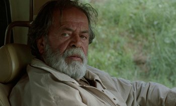 Movie still from “Through the Olive Trees” (1994), directed by Abbas Kiarostami – An old man with a beard and a white mustache; Close Up shot, Low angle