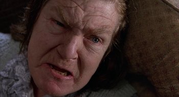 Movie still from “Throw Momma from the Train” (1987), directed by Danny DeVito – An older woman with a frown on her face; Extreme Close Up shot, High angle