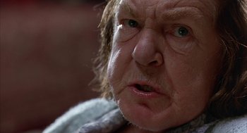 Movie still from “Throw Momma from the Train” (1987), directed by Danny DeVito – An older man with a frown on his face; Close Up shot, Low angle