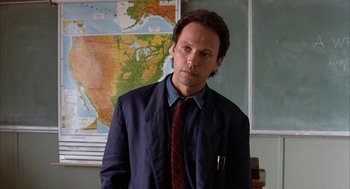 Movie still from “Throw Momma from the Train” (1987), directed by Danny DeVito – A man standing in front of a map in a classroom; Close Up shot, Low angle
