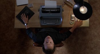 Movie still from “Throw Momma from the Train” (1987), directed by Danny DeVito – A man sitting in front of an old fashioned typewriter; Medium shot, Overhead angle