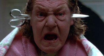 Movie still from “Throw Momma from the Train” (1987), directed by Danny DeVito – An old woman with a knife in her mouth; Close Up shot, Low angle