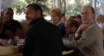 Movie still from “Throw Momma from the Train” (1987), directed by Danny DeVito – A group of people sitting around a table; Medium shot, Over the shoulder angle