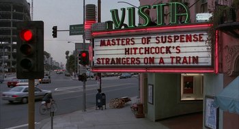 Movie still from “Throw Momma from the Train” (1987), directed by Danny DeVito – A movie theater sign on the side of the street; Extreme Wide shot, Low angle