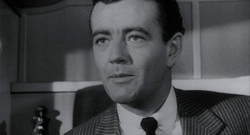 Movie still from “Throw Momma from the Train” (1987), directed by Danny DeVito – An old black and white photo of a man wearing a suit and tie; Close Up shot, Low angle