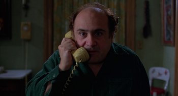 Movie still from “Throw Momma from the Train” (1987), directed by Danny DeVito – A man holding a phone up to his ear; Close Up shot, Low angle