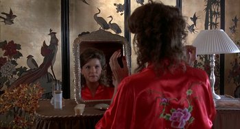 Movie still from “Throw Momma from the Train” (1987), directed by Danny DeVito – A woman in a red robe taking a picture of herself in the mirror; Close Up shot, Over the shoulder angle