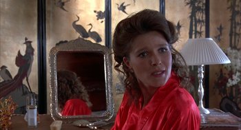 Movie still from “Throw Momma from the Train” (1987), directed by Danny DeVito – A woman in a red robe looking into a mirror; Close Up shot, Over the shoulder angle