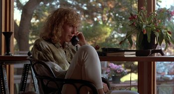 Movie still from “Throw Momma from the Train” (1987), directed by Danny DeVito – A woman sitting at a table talking on a phone; Medium shot, Low angle