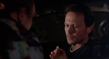 Movie still from “Throw Momma from the Train” (1987), directed by Danny DeVito – A man holding a cigarette in front of another man; Close Up shot, Over the shoulder angle