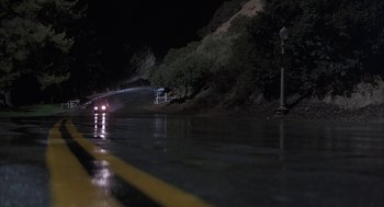 Movie still from “Throw Momma from the Train” (1987), directed by Danny DeVito – A car driving down a street at night; Extreme Wide shot, High angle
