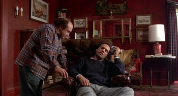 Movie still from “Throw Momma from the Train” (1987), directed by Danny DeVito – Two men are sitting in a living room talking; Medium shot, High angle