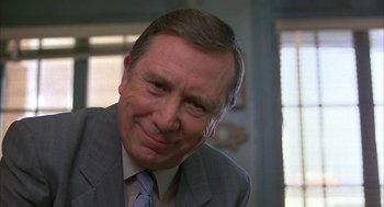 Movie still from “Throw Momma from the Train” (1987), directed by Danny DeVito – An older man wearing a suit and tie smiling; Close Up shot, Low angle