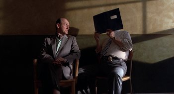 Movie still from “Throw Momma from the Train” (1987), directed by Danny DeVito – Two men in suits sitting on a bench; Medium shot, Low angle