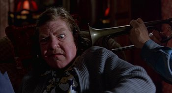 Movie still from “Throw Momma from the Train” (1987), directed by Danny DeVito – An older man with a horn in his hand; Close Up shot, Low angle