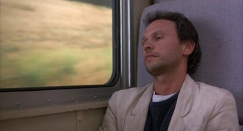 Movie still from “Throw Momma from the Train” (1987), directed by Danny DeVito – A man sitting on a train looking out the window; Close Up shot, Low angle