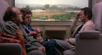 Movie still from “Throw Momma from the Train” (1987), directed by Danny DeVito – A woman sitting on a train looking out the window; Wide shot, Over the shoulder angle