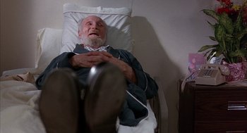 Movie still from “Throw Momma from the Train” (1987), directed by Danny DeVito – An older man laying in a hospital bed; Medium shot, High angle