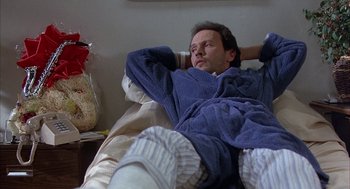Movie still from “Throw Momma from the Train” (1987), directed by Danny DeVito – A man laying on a bed with his feet on the ground; Medium shot, Low angle
