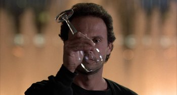 Movie still from “Throw Momma from the Train” (1987), directed by Danny DeVito – A man holding a wine glass in front of his face; Close Up shot, Low angle