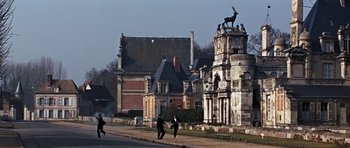 Movie still from “Thunderball” (1965), directed by Terence Young – A group of people walking down a street near a building; Extreme Wide shot, Low angle