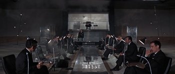 Movie still from “Thunderball” (1965), directed by Terence Young – A group of men in suits sitting in a room; Extreme Wide shot, High angle