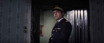 Movie still from “Thunderball” (1965), directed by Terence Young – A man in a military uniform standing in front of a wall; Medium shot, Low angle