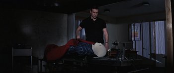 Movie still from “Thunderball” (1965), directed by Terence Young – A man standing next to a bed in a dark room; Medium shot, Low angle