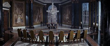 Movie still from “Thunderball” (1965), directed by Terence Young – A group of people sitting at a table in front of a chandelier; Extreme Wide shot, High angle