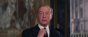 Movie still from “Thunderball” (1965), directed by Terence Young – An older man adjusting his tie in a suit; Close Up shot, Low angle