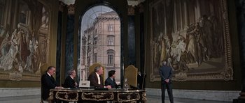 Movie still from “Thunderball” (1965), directed by Terence Young – A group of people sitting at a table in front of a building; Wide shot, Over the shoulder angle