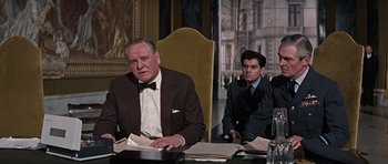 Movie still from “Thunderball” (1965), directed by Terence Young – Two men in suits sitting at a table in front of papers; Medium shot, Over the shoulder angle