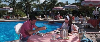 Movie still from “Thunderball” (1965), directed by Terence Young – A man and a woman sitting at a table by the pool; Wide shot, High angle