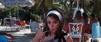 Movie still from “Thunderball” (1965), directed by Terence Young – A beautiful woman with a white headband eating food from a spoon; Medium shot, Over the shoulder angle