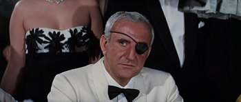 Movie still from “Thunderball” (1965), directed by Terence Young – A man in a white suit and a black eye patch; Close Up shot, Over the shoulder angle
