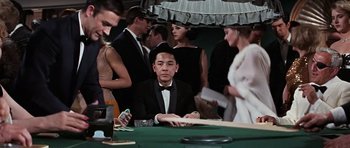 Movie still from “Thunderball” (1965), directed by Terence Young – A group of people standing around a table; Medium shot, High angle