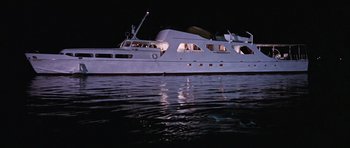 Movie still from “Thunderball” (1965), directed by Terence Young – A large white boat floating on top of a body of water at night; Extreme Wide shot, High angle