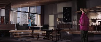 Movie still from “Thunderball” (1965), directed by Terence Young – A woman standing in front of a dining room table; Extreme Wide shot, Low angle