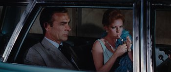 Movie still from “Thunderball” (1965), directed by Terence Young – A man and a woman sitting in the back of a car; Medium shot, Low angle