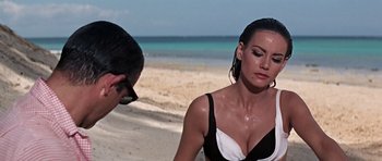 Movie still from “Thunderball” (1965), directed by Terence Young – A woman in a black and white bathing suit on the beach; Close Up shot, Over the shoulder angle