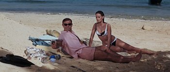 Movie still from “Thunderball” (1965), directed by Terence Young – A man and a woman sitting on the beach; Medium shot, High angle