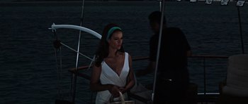 Movie still from “Thunderball” (1965), directed by Terence Young – A woman in a white dress standing on a boat at night; Medium shot, Over the shoulder angle