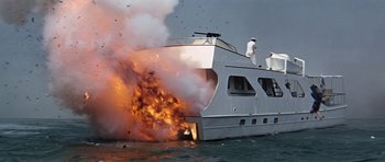 Movie still from “Thunderball” (1965), directed by Terence Young – A boat on fire in the ocean with people standing on it; Extreme Wide shot, High angle