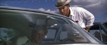 Movie still from “Thunderbolt and Lightfoot” (1974), directed by Michael Cimino – A man in a cowboy hat looking at a woman in a car; Medium shot, Low angle