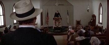 Movie still from “Thunderbolt and Lightfoot” (1974), directed by Michael Cimino – A man standing at a lectern in front of an audience; Wide shot, Low angle