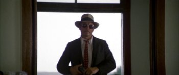 Movie still from “Thunderbolt and Lightfoot” (1974), directed by Michael Cimino – A man in a suit and hat standing in front of a window; Medium shot, Low angle