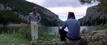 Movie still from “Thunderbolt and Lightfoot” (1974), directed by Michael Cimino – Two men are sitting on the shore of a body of water; Wide shot, Low angle