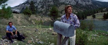 Movie still from “Thunderbolt and Lightfoot” (1974), directed by Michael Cimino – A man standing next to a mailbox in a wooded area; Medium shot, Low angle